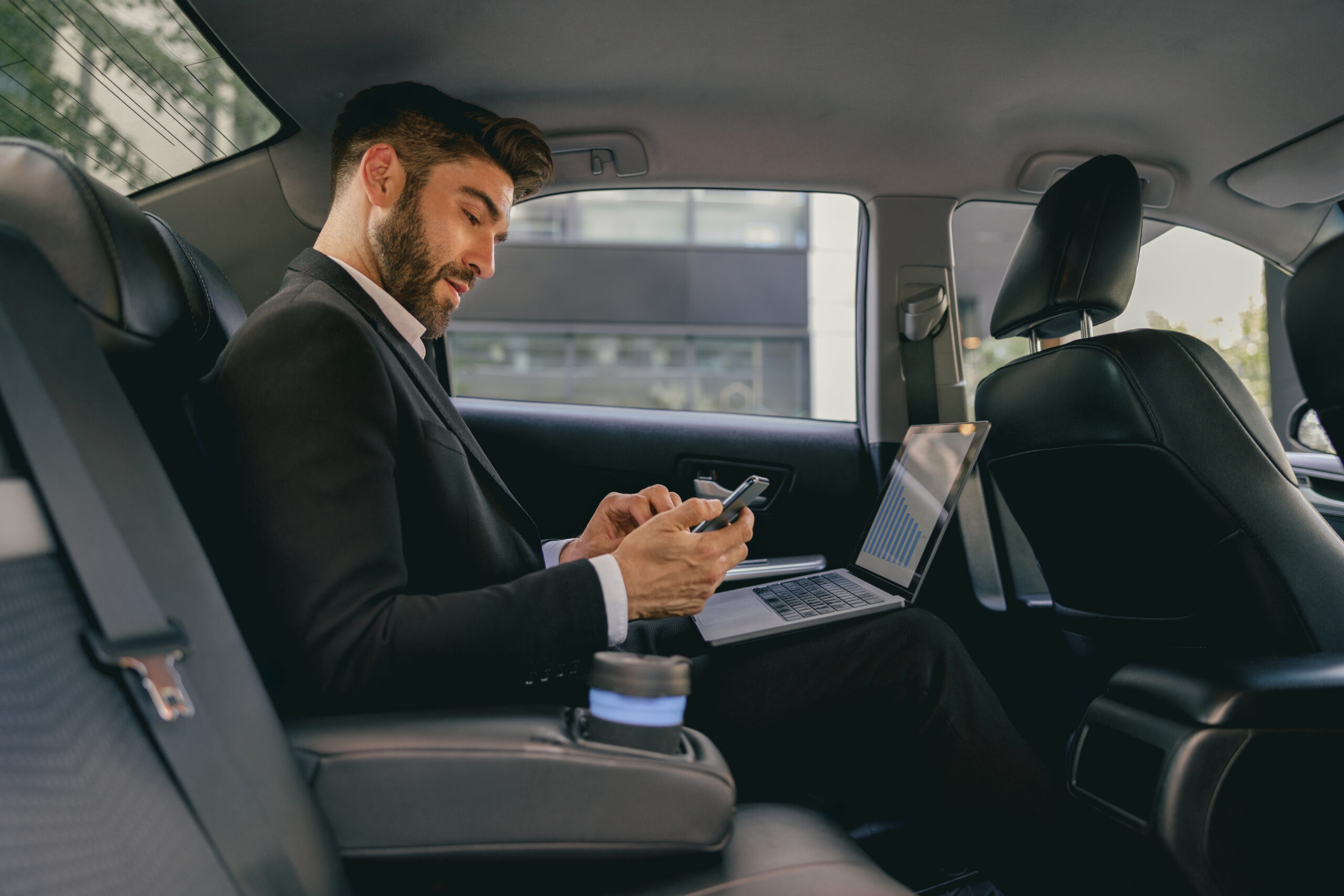 Business professional in car using laptop, representing corporate cab services in Delhi.