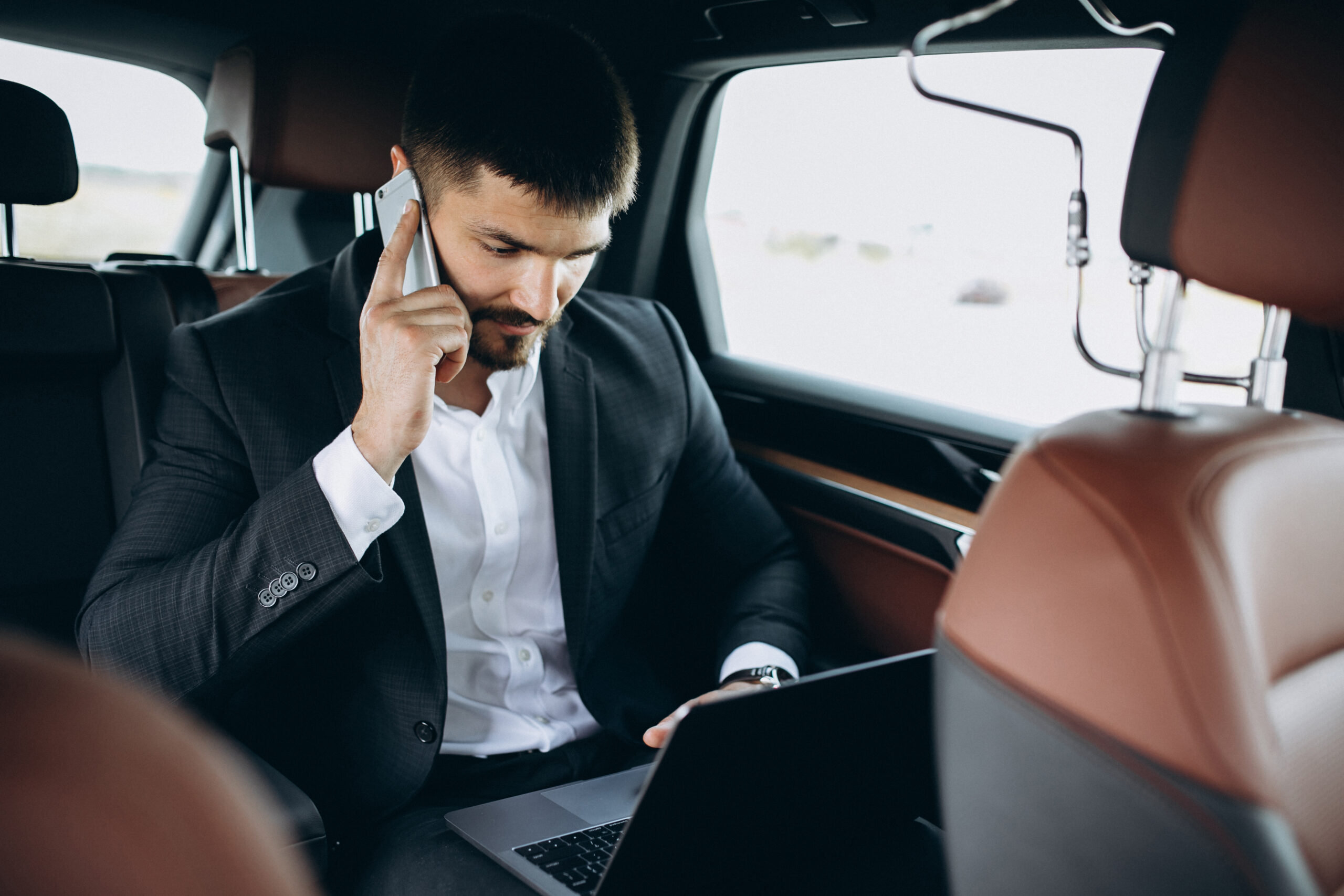 Suit-clad pro working on laptop in car, using phone. Promotes Instant Cab Ride's fleet: economy, luxury, SUV, self-drive options.