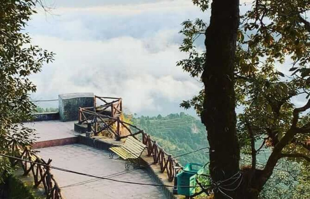 Family road trip to Lansdowne, Uttarakhand, featuring a scenic viewpoint with misty hills and a wooden bench, perfect for a nature getaway