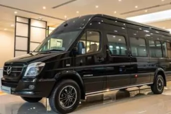 14-seater black Force Urbania rental in Delhi, parked on grass for group tours and outstation trips