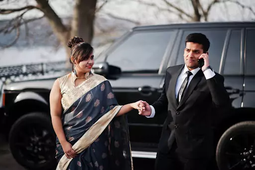 Couple outside black cab, groom on call, planning cabs for Delhi wedding guests